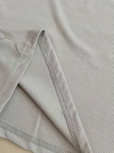 Macro detail of light grey ribbed knit fabric showing high-quality hem stitching