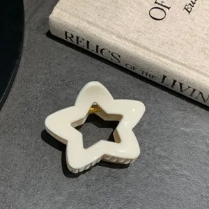 Primo piano di un fermaglio per capelli a forma di stella cava bianco crema per uno stile elegante.