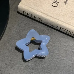 Primo piano dettagliato di molletta per capelli a stella blu chiaro su sfondo grigio testurato.