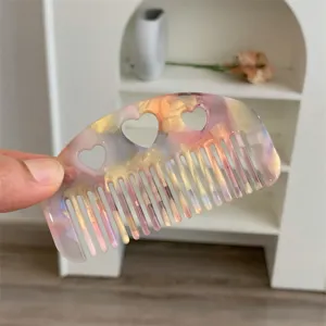 Close-up detail of a small colorful acetate hair comb with cute heart-shaped cutouts.