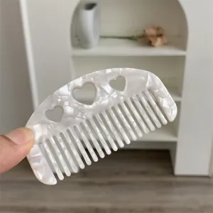 Close-up of marbled white acetate hair comb with delicate heart-shaped cutouts