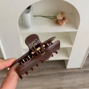 Detalle de pinza para el pelo marrón con doble resorte y dientes de plástico resistentes