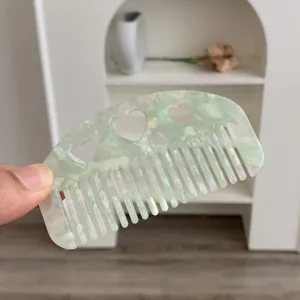 Close-up of small acetate hair comb with heart cutouts in mint green marble