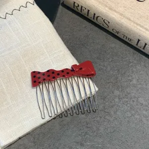 Macro view of a red polka-dot bow hair comb placed on a white fabric with vintage book.