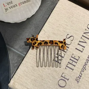 Close-up of a cute leopard print dog acetate hair comb with metal pins on a book