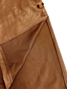 Detailansicht eines braunen Kunstlederkleides mit hohem Schlitz und Schildpatt-Knopf.
