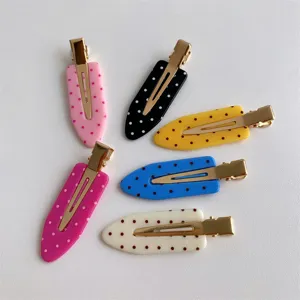 Close-up view of six colorful macaron polka dot hair clips arranged on white background