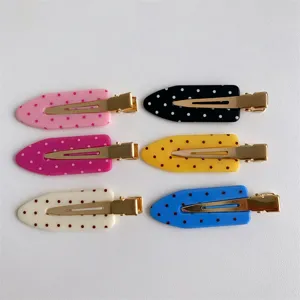 Close-up detail of macaron colored polka dot hair clips with gold-toned metal clips