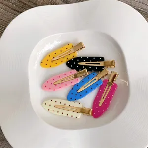 Macro view of colorful macaron polka dot seamless hair clips arranged in a white plate.