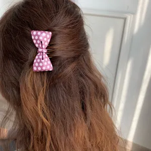 Macro detail of a sweet pink polka dot acetate hair comb clip styled in wavy brown hair