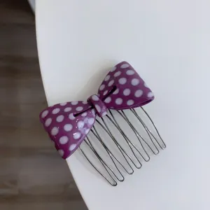 Close-up of a stylish purple polka dot bow hair comb with durable metallic teeth