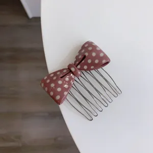 Close-up of pink polka dot acetate bow hair comb with silver metal pins detail