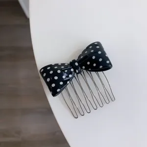 Detailed view of a black polka dot acetate bow hair comb with polished silver teeth