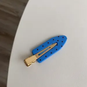 Close-up of blue polka dot seamless hair clip with gold metal base