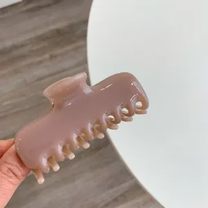 Primer plano de una pinza para el cabello de color malva minimalista sobre fondo blanco.