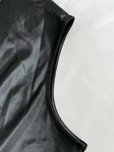 Detailansicht der Armlochnaht und glänzenden Kunstlederstruktur eines schwarzen Kleides.