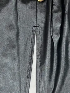 Nahaufnahme der präzisen Nähte und des Schlitzes an einem schwarzen Bodycon-Kunstlederkleid