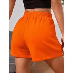 Back view of vibrant orange women's sports shorts with an elastic waistband and loose fit.