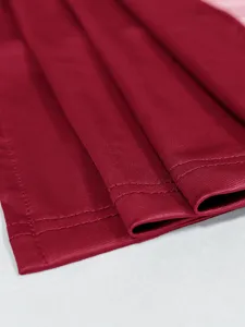 Makroaufnahme des weinroten Kleidsaums mit hochwertigen Doppelnähten und Stoffstruktur.