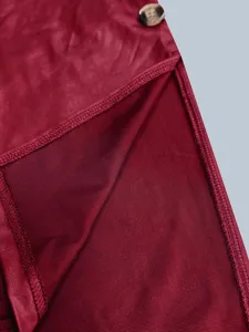 Detaillierte Nahaufnahme eines weinroten Kunstlederkleides mit Seitenschlitz und Marmorknopf