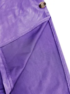 Detailansicht eines lila Kunstlederkleides mit feinen Nähten und einem Zierknopf im Fokus