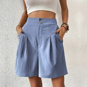 Detail view of high waist pleated wide leg shorts in blue with double buttons and pockets.