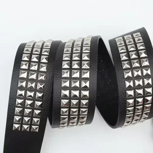 Dettaglio macro di una cintura in pelle nera con tre file di borchie metalliche a piramide argento