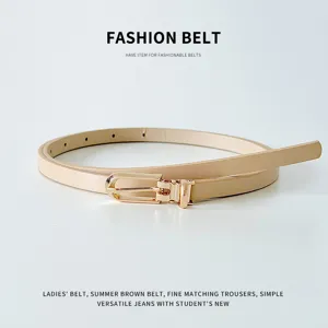 Primo piano di una sottile cintura da donna in pelle PU beige con delicata fibbia metallica.