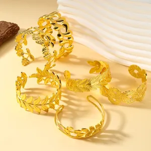 Detail von verschiedenen 18K vergoldeten Titanstahl-Manschettenarmbändern mit Blattmuster.