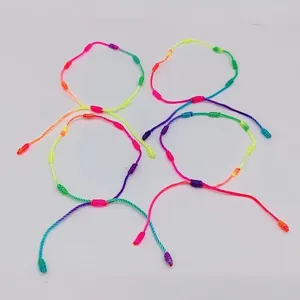 Dettaglio di braccialetti intrecciati a sette nodi fatti a mano con fili arcobaleno