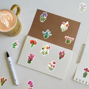 Colorful tulip flower stickers arranged on a notebook with a cup of coffee and pen.