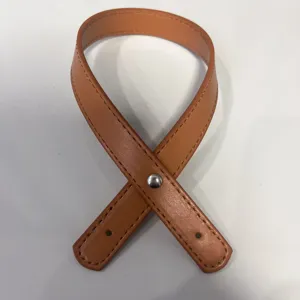 Detalle de un asa de bolso de cuero PU marrón con doble costura y un remache