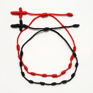 Vista dettagliata di braccialetti in corda rossa e nera intrecciati a mano con nodi a croce.