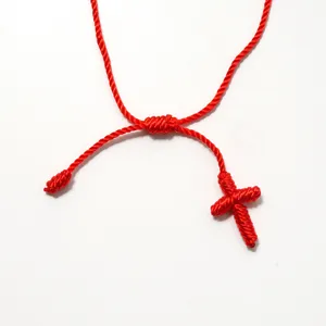 Dettaglio di un bracciale a croce intrecciato rosso fatto a mano con nodo scorrevole