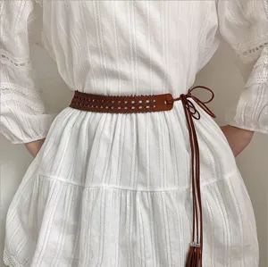 Detailed view of a brown woven waist belt worn on a white dress, perfect retro accessory.
