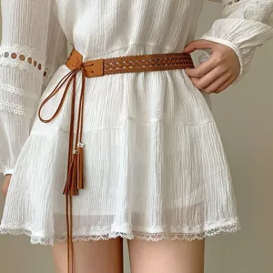 Primo piano della cintura intrecciata marrone con nappe su un abito di pizzo vintage.