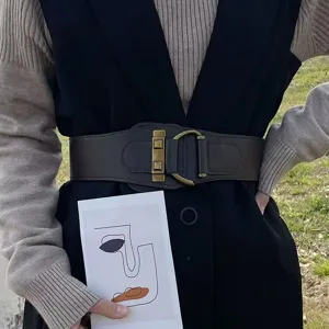 Dettaglio di una cintura elastica larga marrone scuro con fibbia in ottone vintage su modella