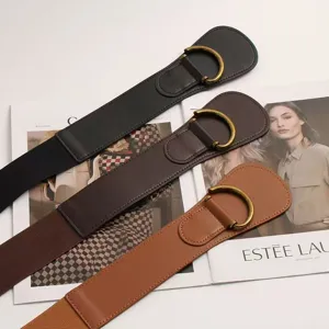 Primo piano di tre eleganti cinture elastiche larghe con fibbie a D su sfondo di rivista