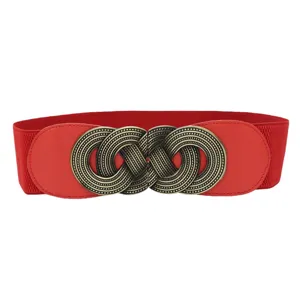 Primo piano della cintura elastica rossa larga con fibbia in bronzo antico intarsiata.