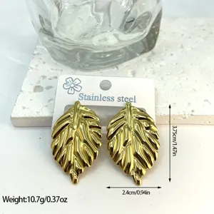 Macro detail of gold leaf shaped stainless steel earrings showing dimensions and weight info