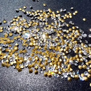 Gros plan détaillé de strass pointus scintillants, cristaux dorés et transparents pour ongles.