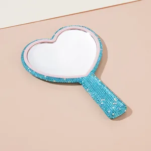 Detailed view of the sparkling blue rhinestone heart-shaped handheld makeup mirror handle.