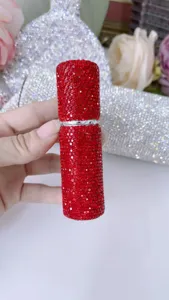 Primer plano de un frasco de perfume de viaje de 5ml con pedrería roja de lujo.