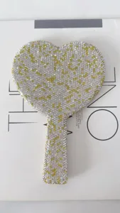 Detail view of heart shaped hand mirror encrusted with sparkling clear and yellow rhinestones.