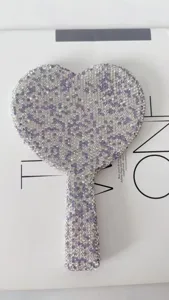 Close-up detail of glittering rhinestone heart hand mirror surface, sparkling crystal texture.