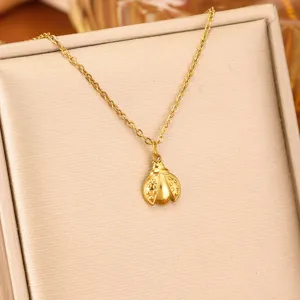 Detailed macro view of a delicate gold ladybug pendant necklace on a beige display.