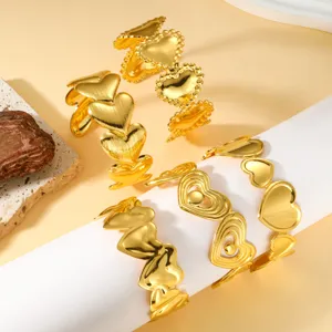 Primer plano de cuatro brazaletes de acero inoxidable bañados en oro de 18 quilates con forma de corazón.
