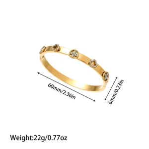 Macro detail of the gold titanium steel bangle featuring crystal-set clover motifs and dimensions