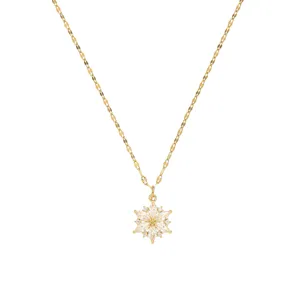 Primer plano de collar con colgante de flor dorada y piedras de circonita clara