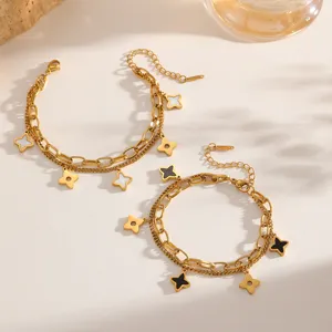Detailansicht eines goldfarbenen zweilagigen Armbands mit Kleeblatt-Anhängern.